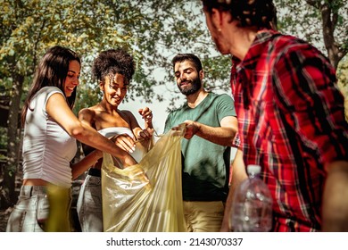 Group of young people collecting trash for recycling in the wilderness - multiethnic friends after picnic limiting their  environmental footprint  - Powered by Shutterstock