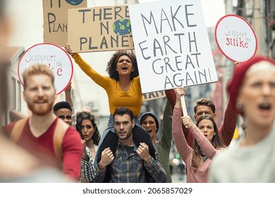 Group of young people demonstrate against climate change. Angry women and men strike with boards and signs in support of our planet. Group of activists protest and march to save the planet.