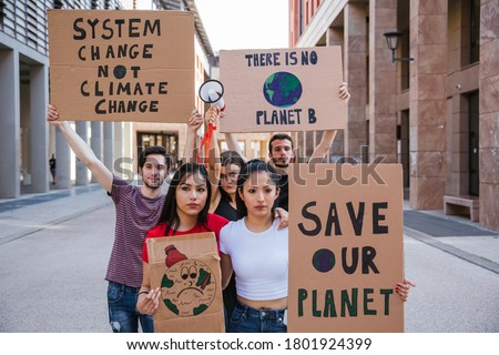 Group of young people at a demonstration for the environment - Young millennials protest at a procession to save the planet with slogans and drawn in the sign - Concept of manifestation