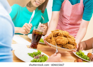 Group Of Young People At Dining Table Ready To Eat Fried Chicken Being Served By The Waiter In Restaurant