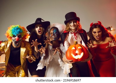 Group of young people dressed up as spooky characters having fun at Halloween costume party. Adult male and female friends with scary makeup on faces doing claw gesture, hissing and making grimaces - Shutterstock ID 2196918697