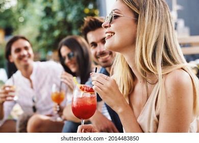 Group of young people drinking cocktails at a summer bar during the day - Shutterstock ID 2014483850