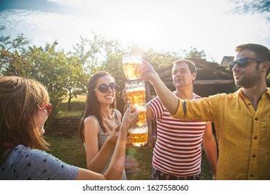 Group of young people enjoying and cheering beer outdoors.