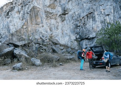 Group of young people at the foot of the mountain unloading gear from the car to practice rock climbing. Rocky terrain at the foot of the mountains. - Powered by Shutterstock