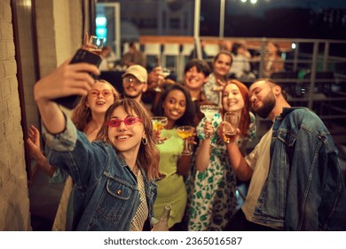 Group of young people, friends meeting on rooftop in evening, having good time together, taking selfie. Concept of party, leisure time, fun and joy, weekends, celebration, youth culture - Powered by Shutterstock