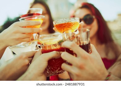 Group of young people, friends raises their glasses in cheerful toast, celebrating together under warm sunlight. Concept of party, Friday mood, celebration, summer holidays, relax. - Powered by Shutterstock