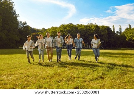 Group of a young people friends walking in the summer park. Happy people girls and boys having fun and running outdoors. Smiling students in casual clothes spending time together on the lawn.