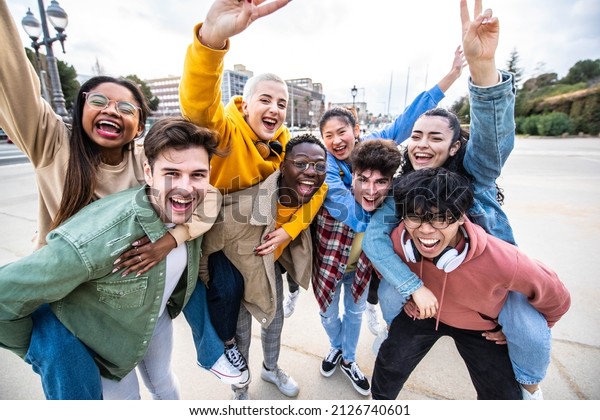 Group of young people with hands up looking\
at camera - Millenial friends having fun together on city street -\
Multicultural students walking outside university campus - Youth\
culture and scholarship