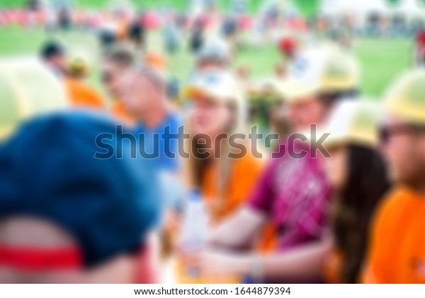 \
a group of young\
people have fun and drink together at a race festival (Orange dutch\
racing fans, supporters), brurred picture, people drinking alcohol\
in the summer