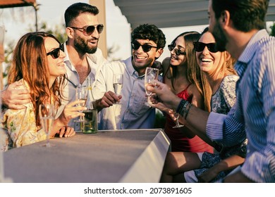 Group of young people having a fun party drinking champagne together standing at the garden - friends toasting sparkling wine - Powered by Shutterstock