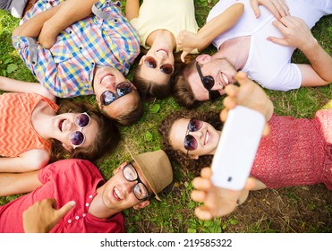 Group Of Young People Having Fun In Park, Lying On The Grass