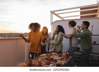 group of young people having fun at home on the roof terrace dancing and drinking alcohol - Powered by Shutterstock