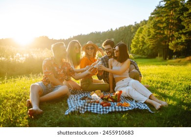 Group of young people having fun while drinking beer at picnic party. Friends enjoy sunny day. Vacation, weekend, friendship or holliday concept. - Powered by Shutterstock