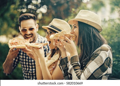 Group Of Young People Having Fun In The Park And Eating Pizza.