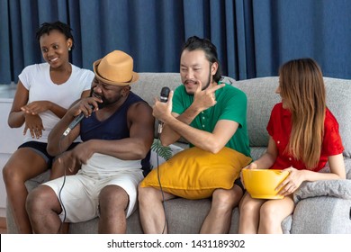 Group Of Young People Having A House Party Together. African American, Asian Man And Woman. Enjoy Singning Together. Mix Race Party Concept.