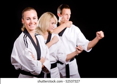 Group of young people in kimono in martial arts training and exercising taekwondo in gym over black background. - Powered by Shutterstock