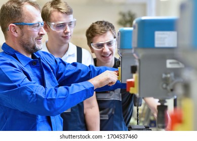 Group of young people in mechanical vocational training with teacher at drilling machine 