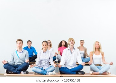 group of young people meditating in office at desk, group meditation - Powered by Shutterstock