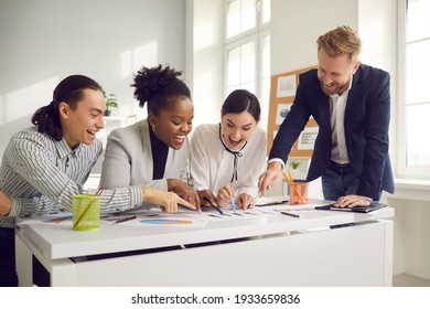 Group Of Young People Meeting Around Office Table. Happy Successful Business Team Sitting At Desk, Working On Project, Analyzing Data Report, Setting Goals, Developing New Product, Enjoying Teamwork