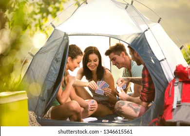 
Group of young people on camping trip in countryside sitting in tent and playing cards - Powered by Shutterstock