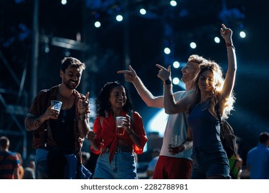 A group of young people are partying at a live event held outdoors on a summer night - Shutterstock ID 2282788981