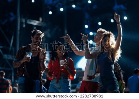 A group of young people are partying at a live event held outdoors on a summer night