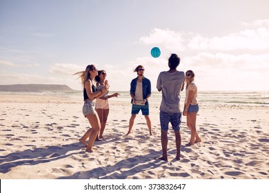 Group of young people playing with ball at the beach. Young friends enjoying summer holidays on a sandy beach. - Powered by Shutterstock