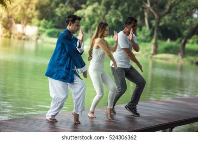 Group of young people practicing traditional Tai Chi Chuan, Tai Ji  and Qi Gong for fighting match together in the park on the lake background, traditional chinese martial arts concept. - Powered by Shutterstock