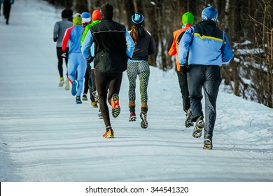 Group Young People Running Together Snowy Trail In Winter Park. Rear View