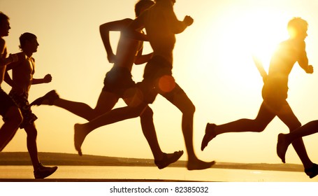 group of young people runs at the beach on beautiful summer sunset