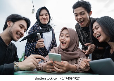 group of young people saw with his friend's handphone - Shutterstock ID 1474094927