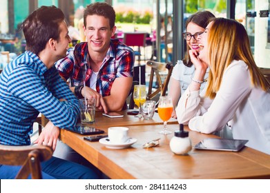 Group Of Young People Sitting At A Cafe, Talking And Enjoying