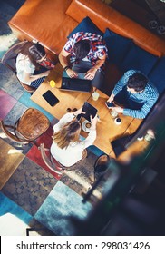 Group Of Young People Sitting At A Cafe, With Mobiles And Tablets, Top View