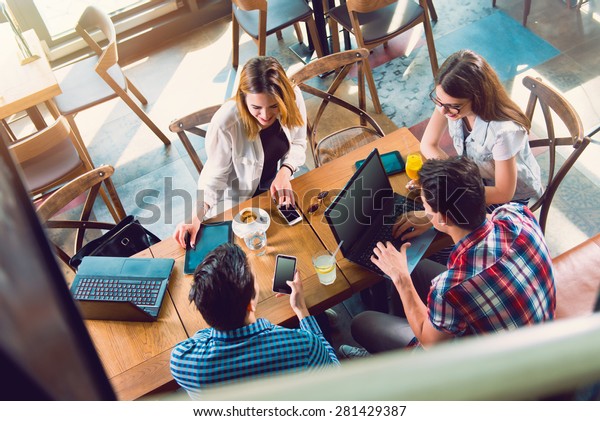Group of young people sitting at a cafe, talking and\
enjoying, top view