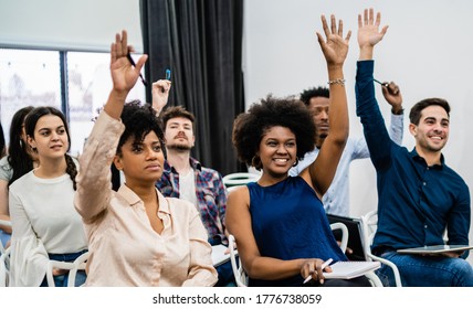 Group Of Young People Sitting On Conference Together While Raising Their Hands To Ask A Question. Business Team Meeting Seminar Training Concept.