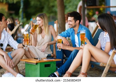 Group of young people sitting in a summer cafe drink beer and chat - Shutterstock ID 2156583459