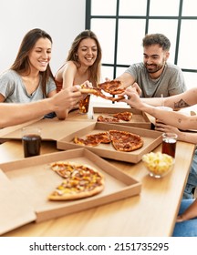 Group Of Young People Smiling Happy Eating Italian Pizza Sitting On The Table At Home