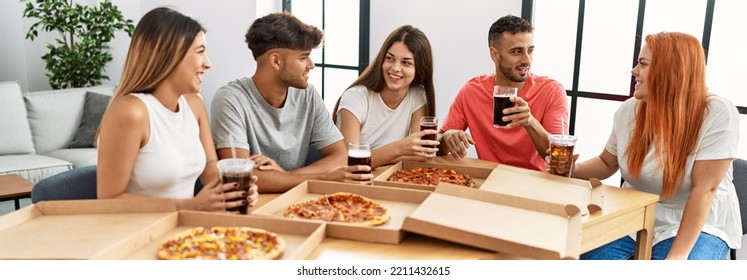 Group of young people smiling happy eating italian pizza sitting on the table at home - Powered by Shutterstock