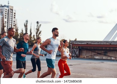 Group of young people in sports clothing jogging together outdoors  - Shutterstock ID 1472680658