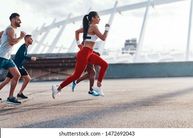 Group of young people in sports clothing jogging together outdoors 
