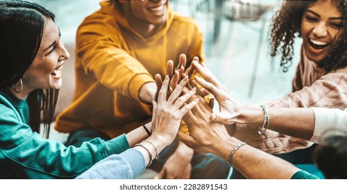 Group of young people stacking hands together - Friends with stack of hands showing unity and teamwork - Human relationship concept - Powered by Shutterstock