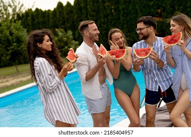 Group Of Young People Standing By The Swimming Pool And Eating Watermellon In The House Backyard