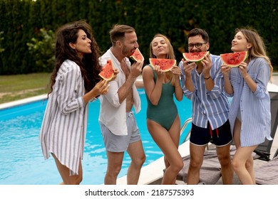 Group Of Young People Standing By The Swimming Pool And Eating Watermelon In The House Backyard