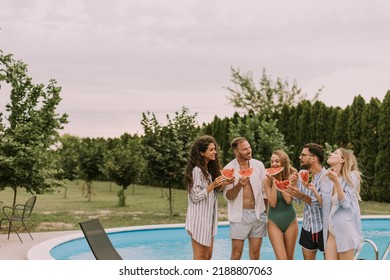 Group Of Young People Standing By The Swimming Pool And Eating Watermellon In The House Backyard