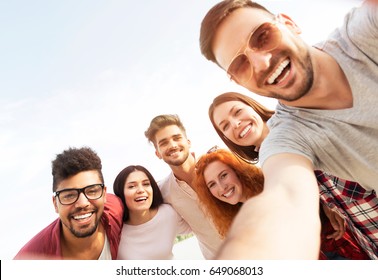Group of young people standing in a circle, outdoors, making a selfie  