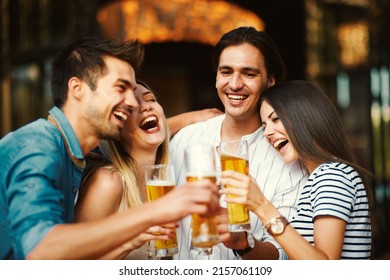 Group of young people at a summer bar toast with beer - Shutterstock ID 2157061109