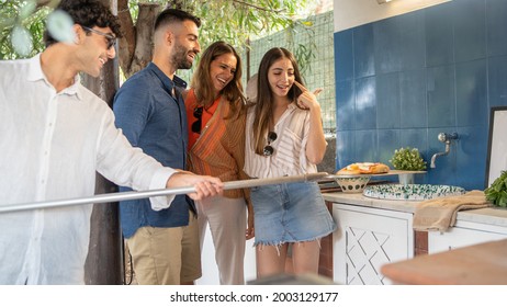 Group Of Young People Taking Away A Margherita Pizza From The Stone Oven. Friends Having Fun With A Pizza Party.