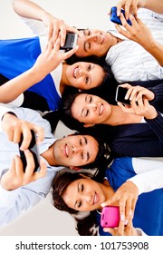 Group Of Young People Texting On Their Cell Phones And Smiling