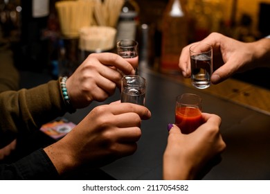 group of young people toasting with mexican tequila shots and tomato juice at bar counter - Powered by Shutterstock