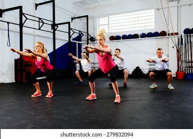 Group Of Young People Training Squats At Gym Class.